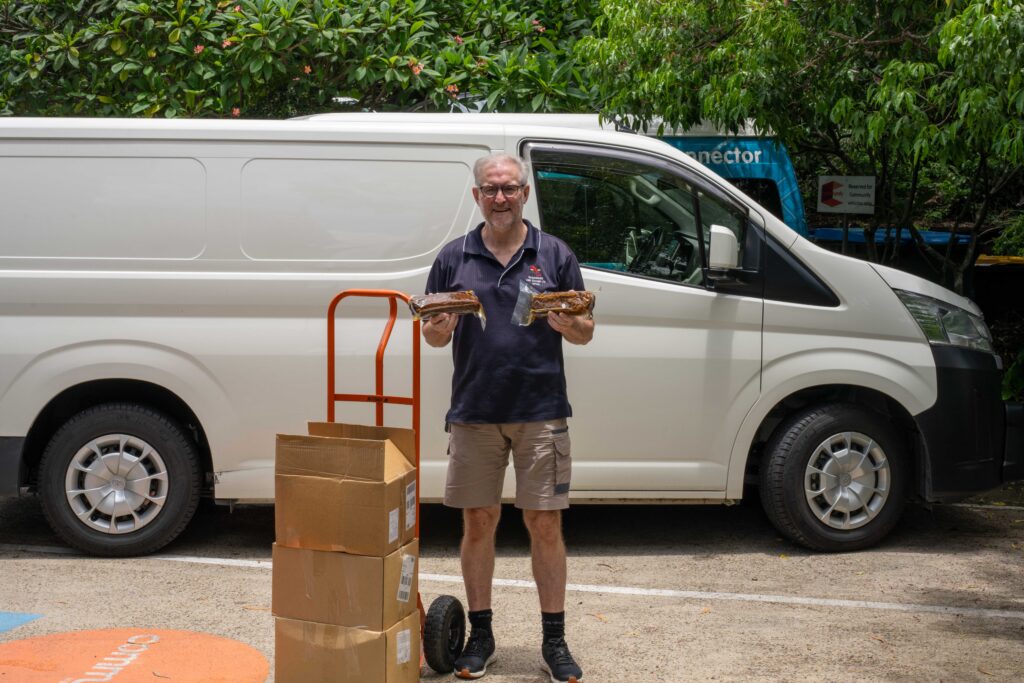 Volunteer with food relief boxes standing next to a van