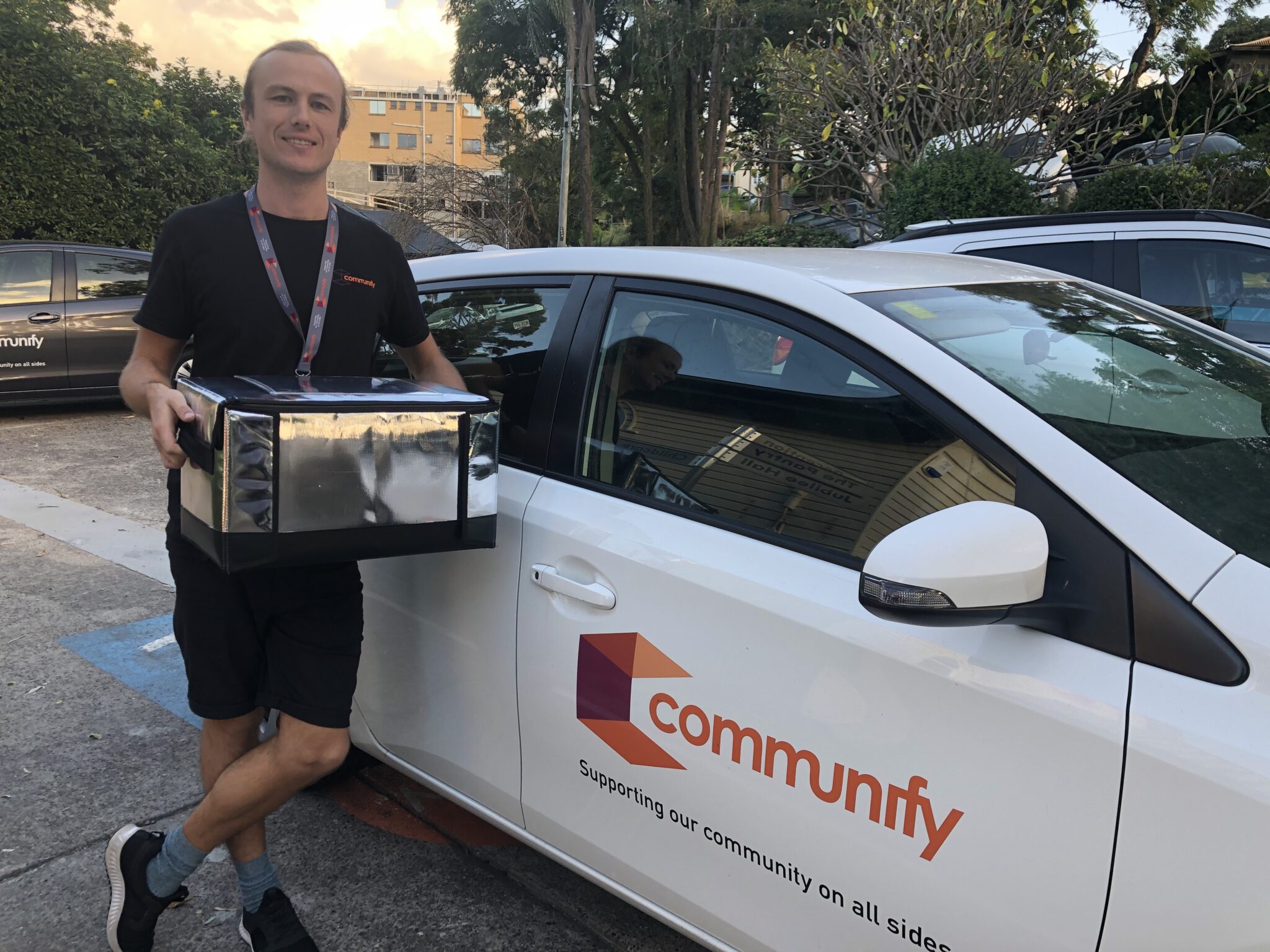 Volunteer with meals standing next to car